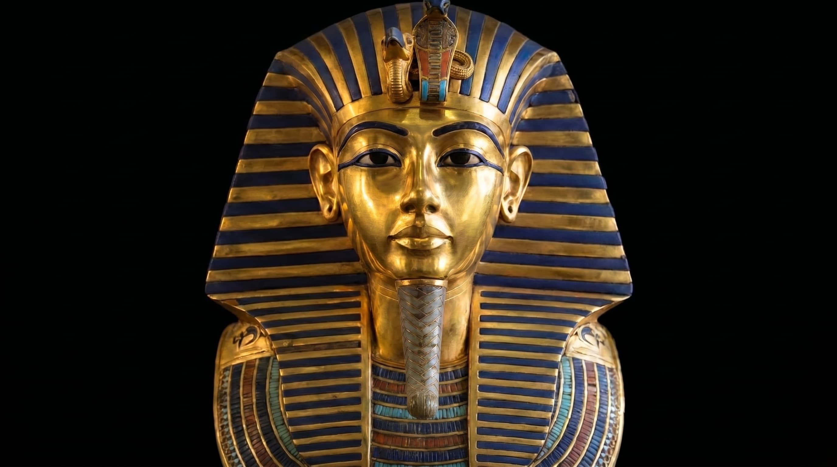 The gold funerary mask of Tutankhamun against a black gallery wall