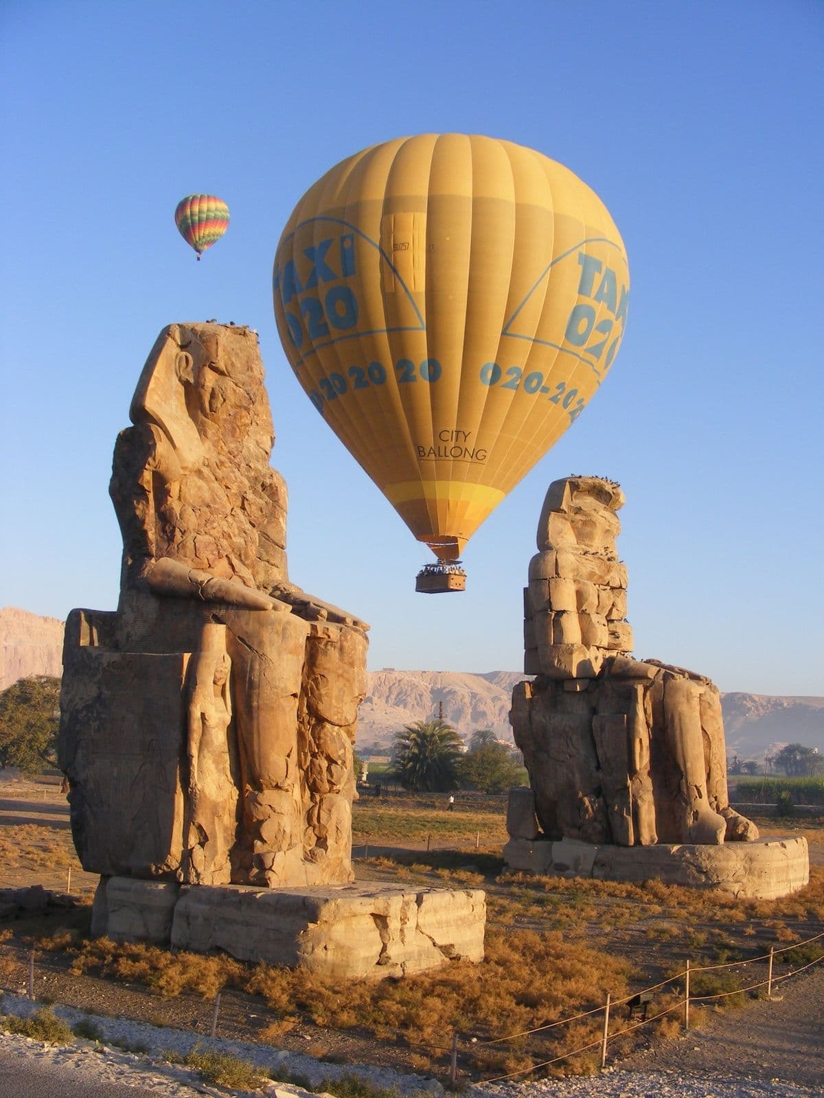 Hot-air balloons drifting over the Colossi of Memnon at sunrise